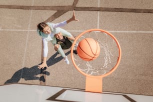 Um pai e uma filha adolescente jogando basquete do lado de fora na quadra, visão de ângulo alto acima da rede de aro. Um pai e uma filha adolescente jogando basquete do lado de fora na quadra, visão de ângulo alto acima da rede de aro. Um pai feliz e uma filha adolescente jogando basquete do lado de fora na quadra, de alto nível.