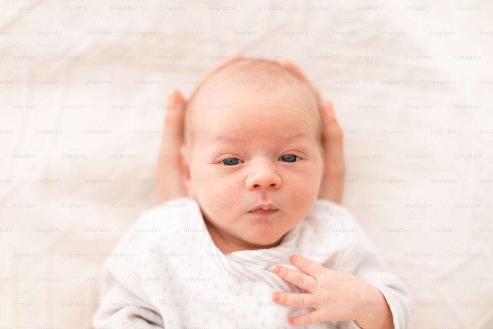 An unrecognizable mother holding her newborn son at home, close-up