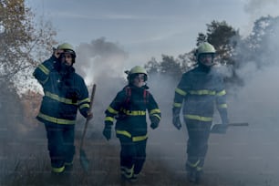 森の火事を止めるためにシャベルで煙の中を走る消防士の男性。