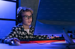 A young gamer boy with headphones playing computer video game.