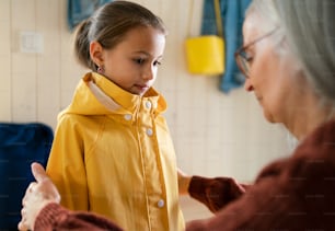 Una abuela ayudando a su nieta a prepararse para salir de casa para ir a la escuela.