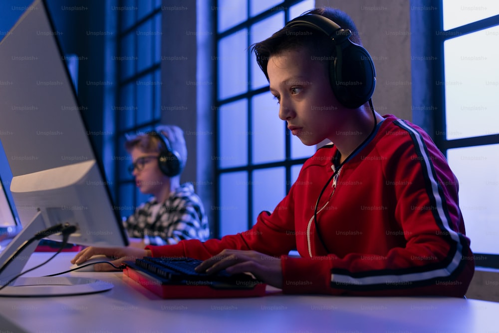 Young gamer boys with headphones playing a computer video game.