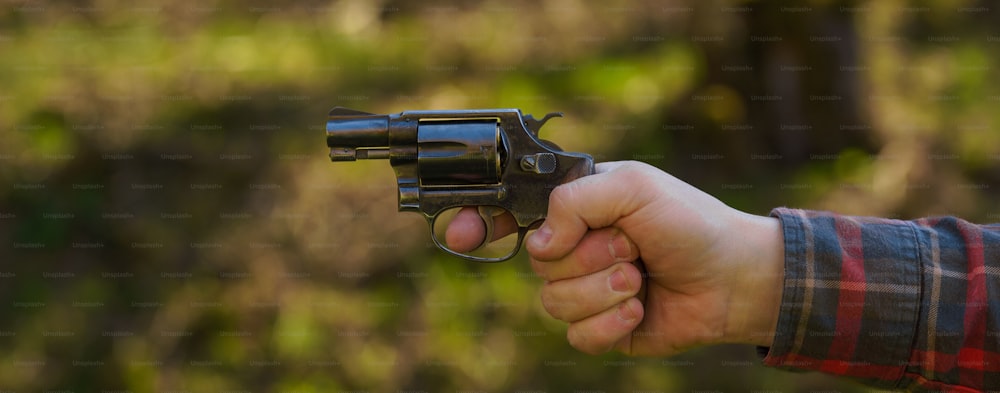 Un homme méconnaissable avec un revolver sur une cible de tir sur un champ de tir en plein air.