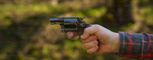 Un uomo irriconoscibile con un bersaglio di puntamento del revolver al poligono di tiro che si allena all'aperto.