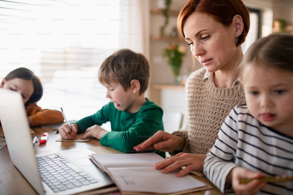 A mother of little children working on laptop when distance learning and doing artwork at home.