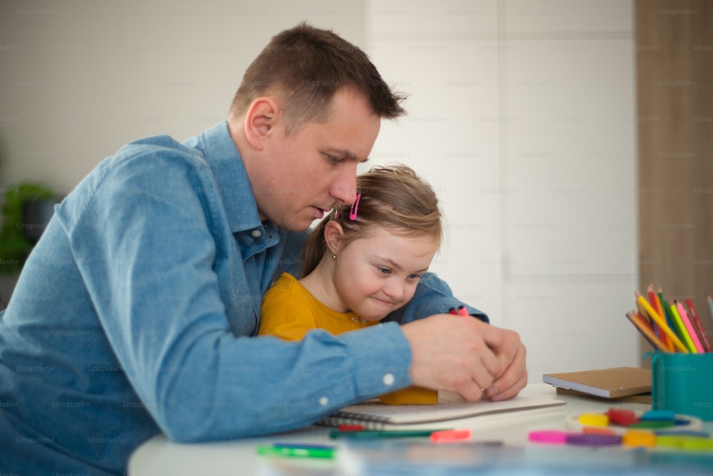 Ein Vater mit seiner kleinen Tochter mit Down-Syndrom lernt zu Hause.