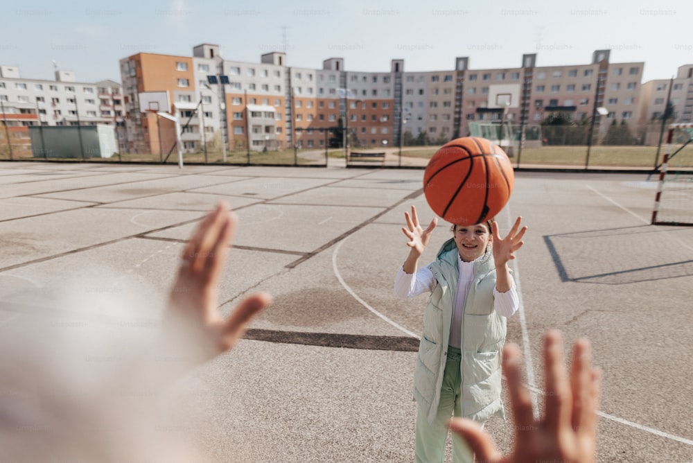 A happy father and teen daughter playing basketball outside at court.