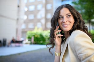 Una exitosa mujer de negocios feliz que viaja por la mañana en la calle de la ciudad, llamando por teléfono móvil.