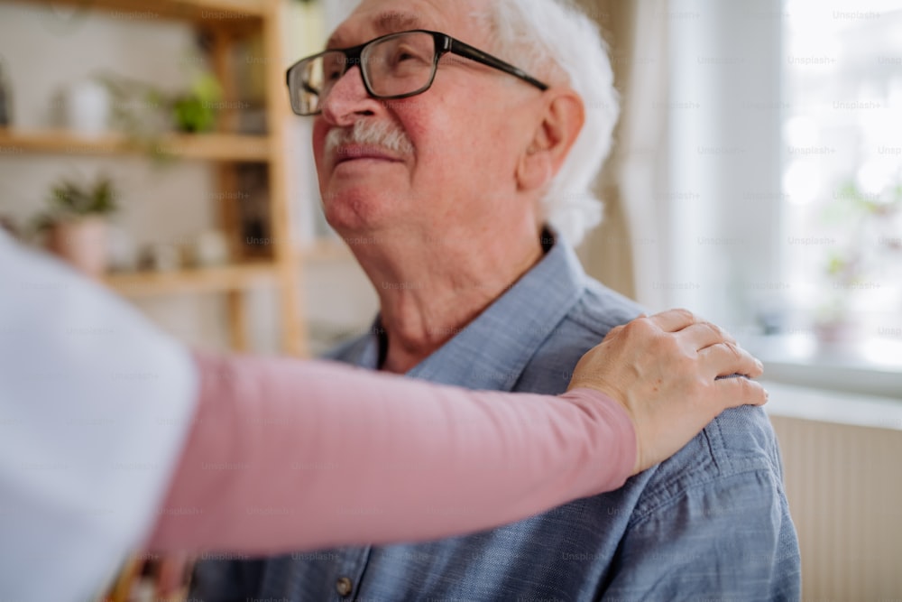 Un operatore sanitario o un caregiver che visita un uomo anziano all'interno della casa.