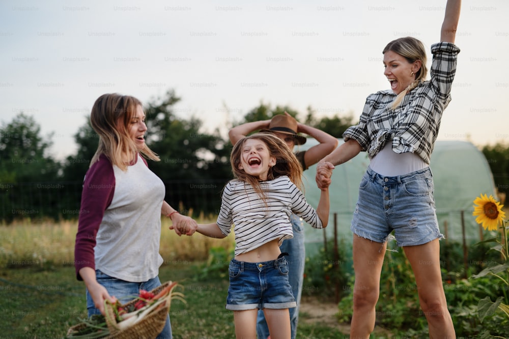 Una niña feliz con su madre y su tía saltando al aire libre en una granja comunitaria.