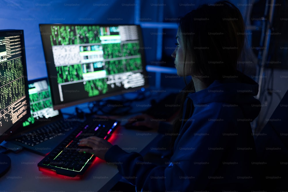 Una joven hacker por computadora en el cuarto oscuro por la noche, concepto de guerra cibernética.