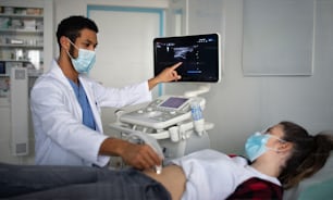 Un jeune médecin examine une jeune femme à l’aide d’un appareil à ultrasons en clinique, concept de coronavirus.