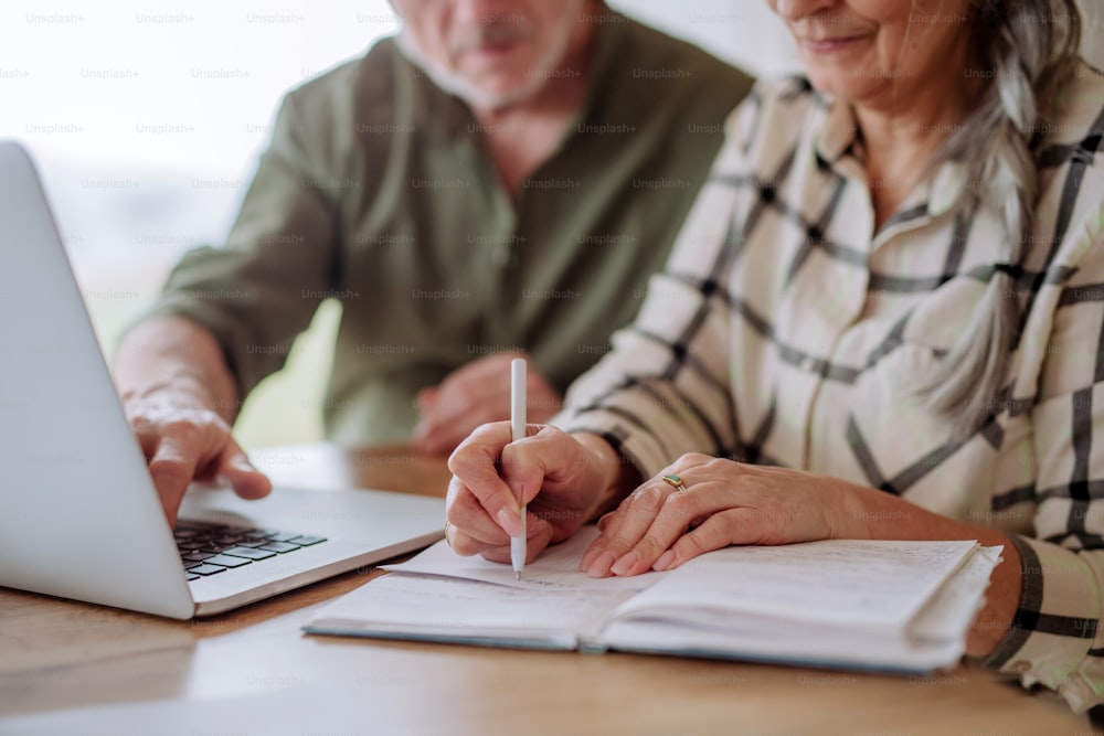 Close up, a stressed senior couple calculate expenses or planning budget together at home.