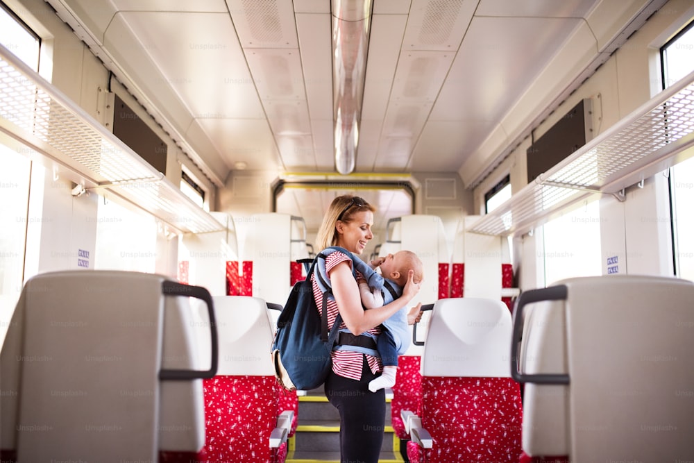 Young mother travelling with baby boy by train. Railway journey of a beautiful woman and her son.