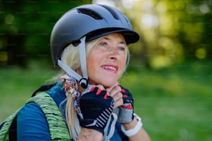 夏の公園で自転車に乗るアクティブなシニアカップル、女性はヘルメットをかぶっている、健康的なライフスタイルのコンセプト。