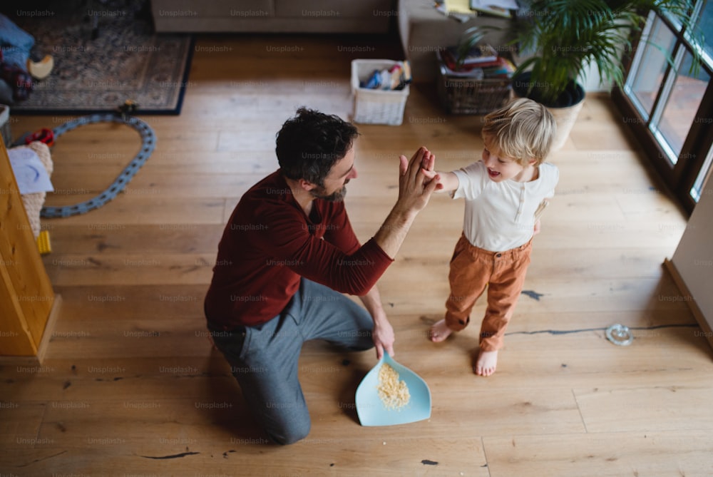 家で掃除をした後、小さな息子とハイファイブする父親のハイアニバーシティビュー、毎日の家事のコンセプト。