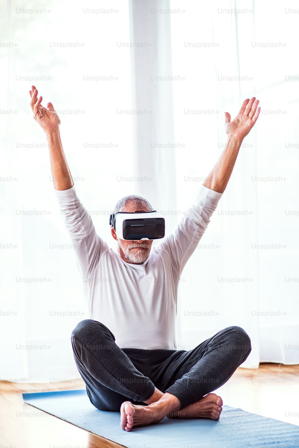 Active senior man with VR goggles doing exercise at home.
