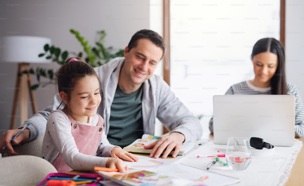 Parents with school girl indoors at home, distance learning and home office concept.