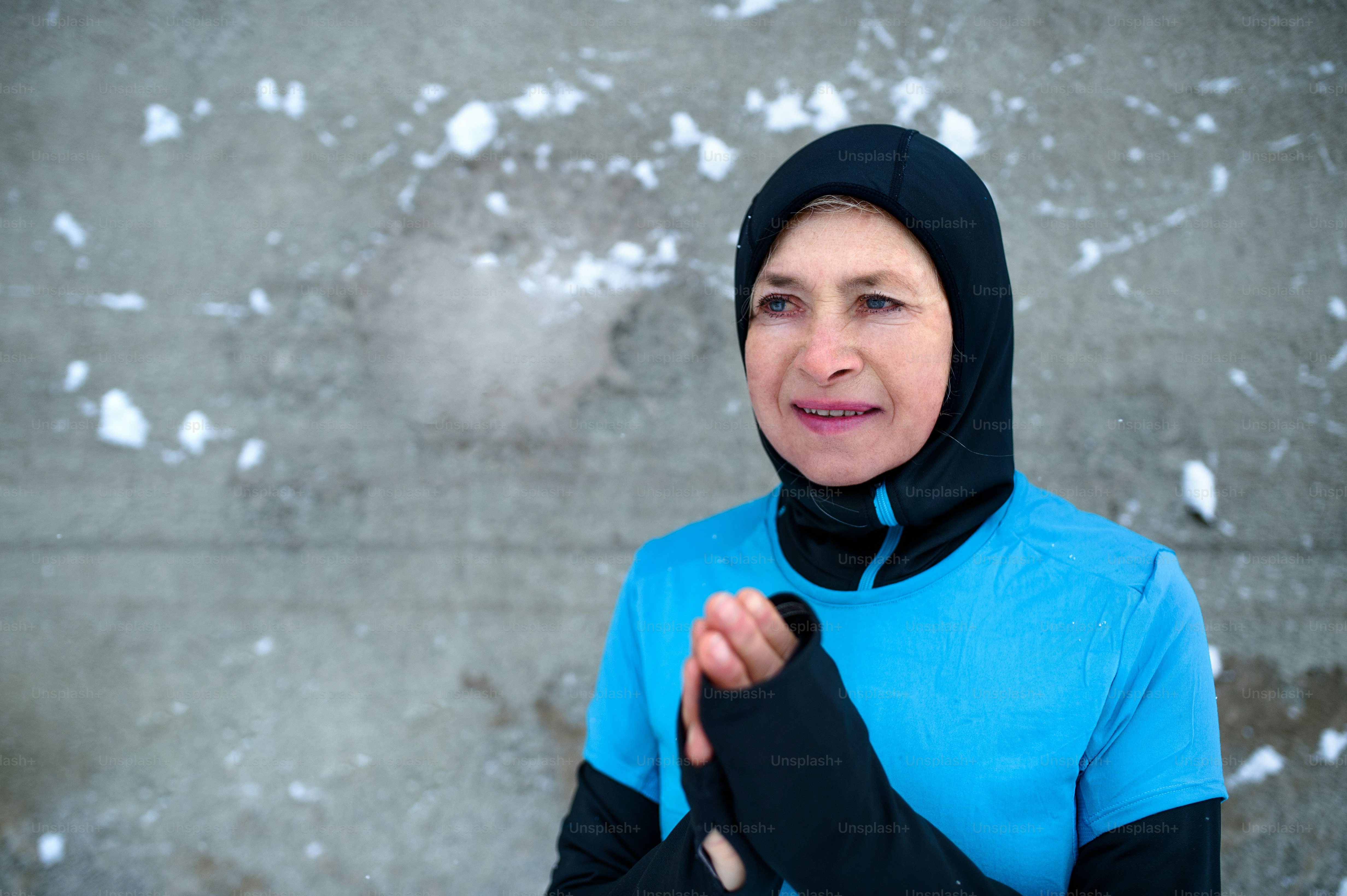 Porträt einer aktiven Seniorin, die im verschneiten Winter draußen an der Wand steht. Speicherplatz kopieren.