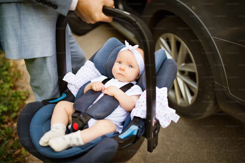 Unrecognizable man carrying his baby girl in a car seat., going into the car.