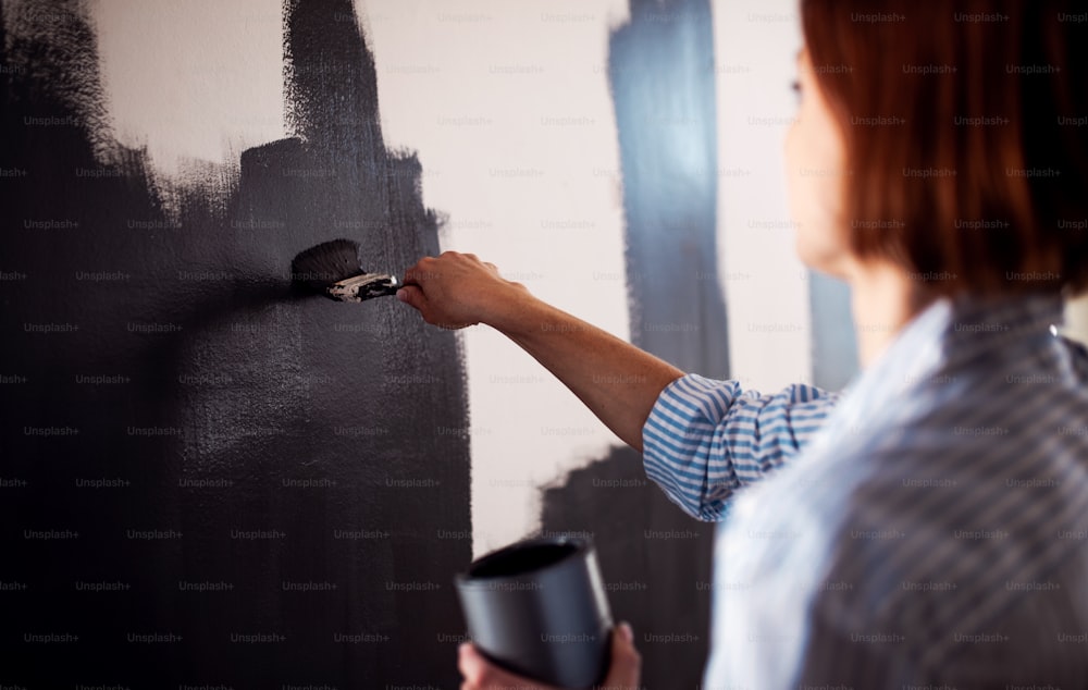 벽을 검은색으로 칠하는 젊은 창조적인 여성. 중소기업의 스타트 업.