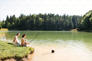 Giovane madre e padre con la figlia al lago. Caldo estivo e acqua.