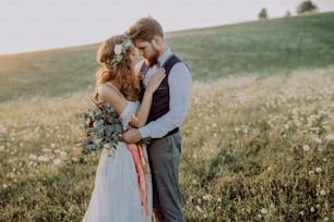 Young bride and groom outside in green nature at romantic sunset.