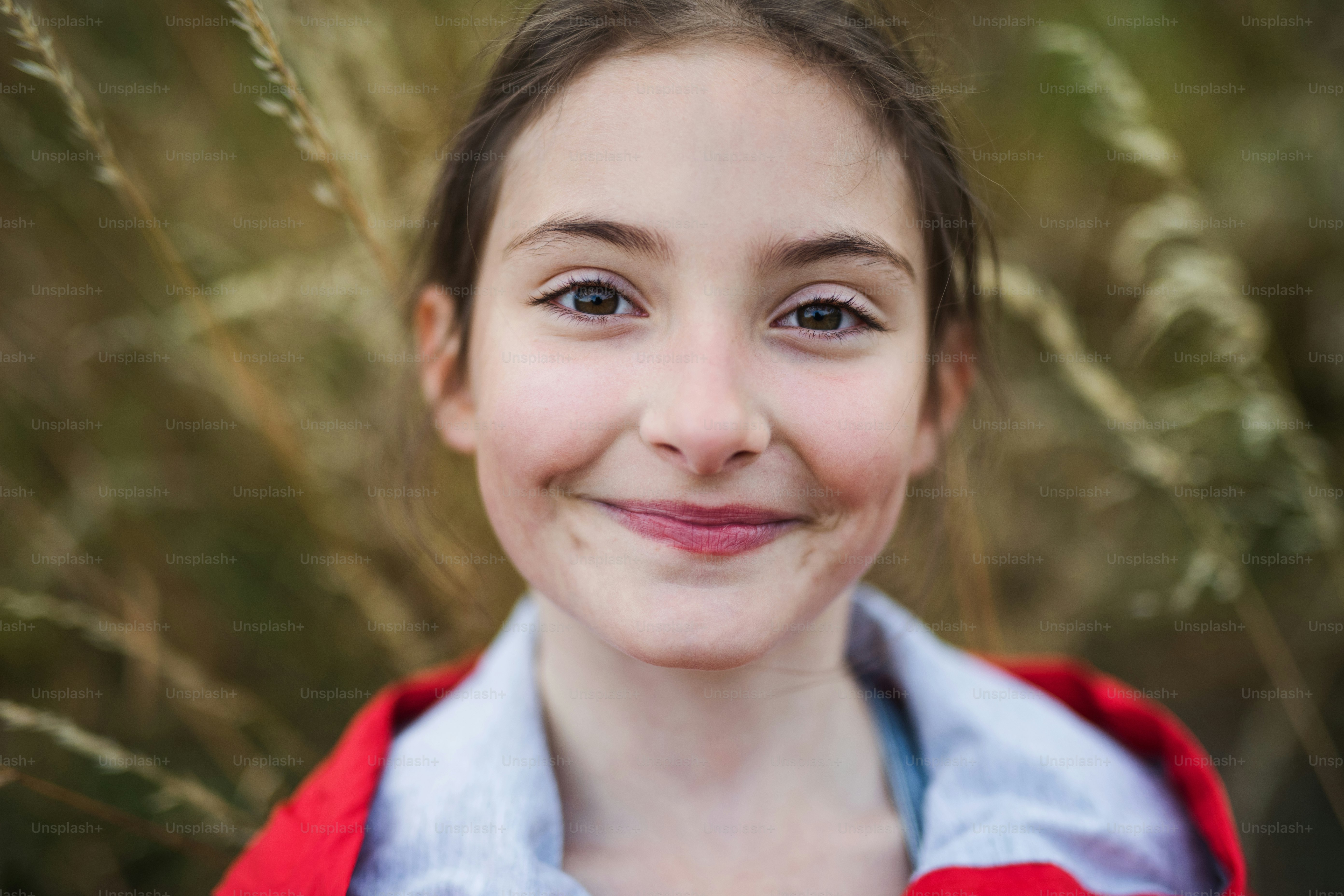 Portrait of school child standing on field trip in nature, looking at
