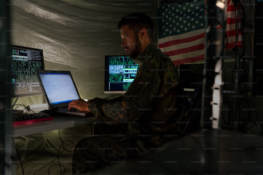 An American hacker in military unifrorm on dark web, cyberwar concept.