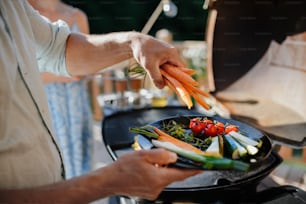 An unrecognizable man preparing vegetables for grilling during family summer garden party, close-up
