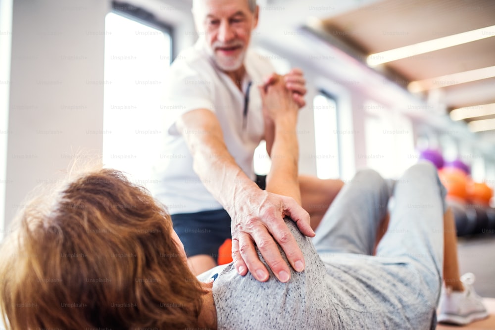 Senior physiotherapist working with an old female patient.