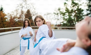 A group of young women practising karate outdoors on terrace.