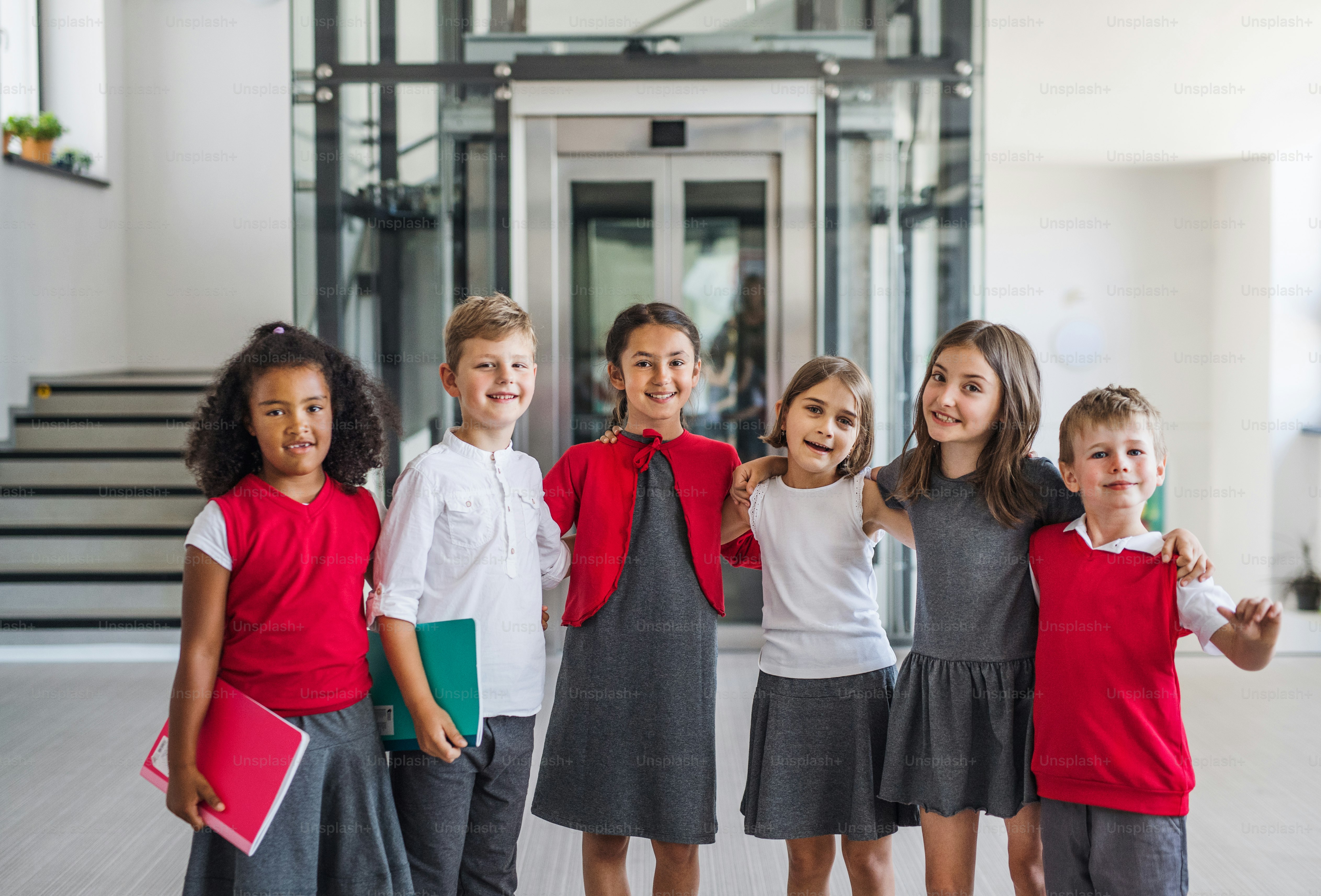 A group of cheerful small school kids in corridor, looking at camera. Back to school concept