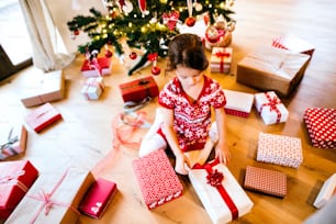 Bella bambina sotto l'albero di Natale che apre i regali.