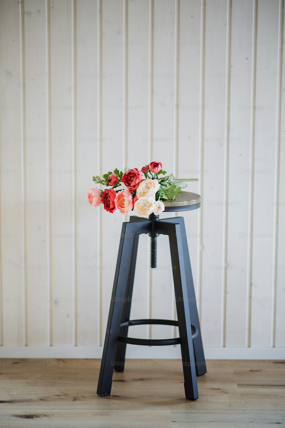 Un bouquet de fleurs sur un tabouret en bois contre un mur de fond blanc. Espace de copie.