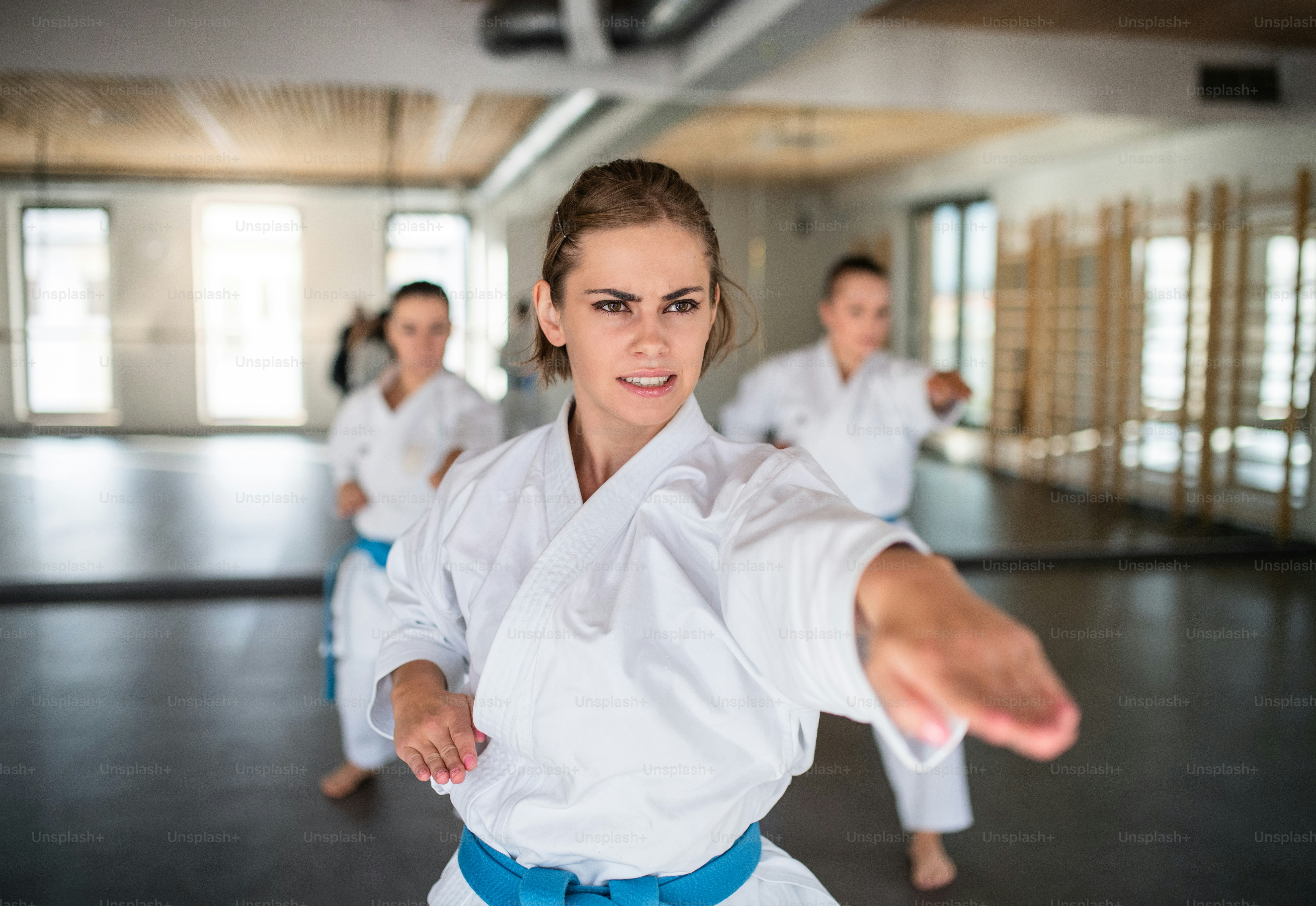 Un gruppo di giovani donne che praticano karate al chiuso in palestra.