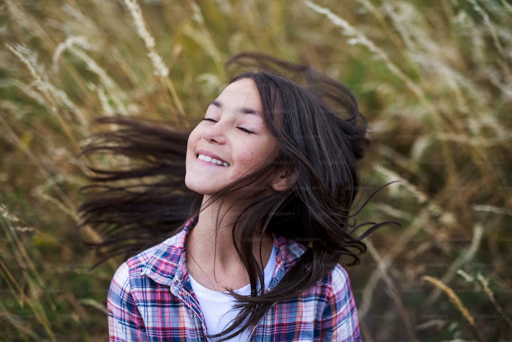 Portrait of school child standing on field trip in nature, eyes closed.