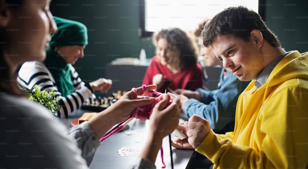 Groupe de personnes heureuses jouant aux cartes et aux jeux de société dans le centre communautaire, inclusion des personnes handicapées.