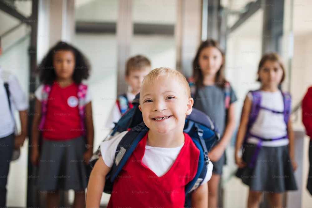 ダウン症の男子生徒が鞄を持ち、廊下を歩いている子供たちのグループ。