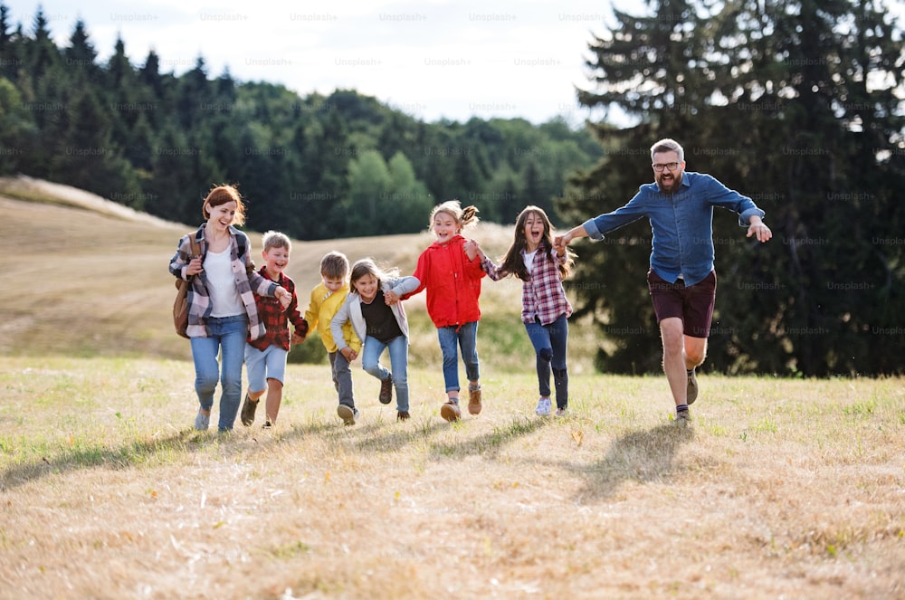 Un grupo de niños pequeños de la escuela con el maestro en una excursión en la naturaleza, corriendo.