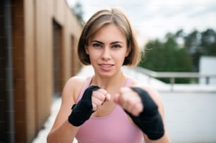 Una vista frontale di una giovane donna che pratica karate all'aperto sulla terrazza.