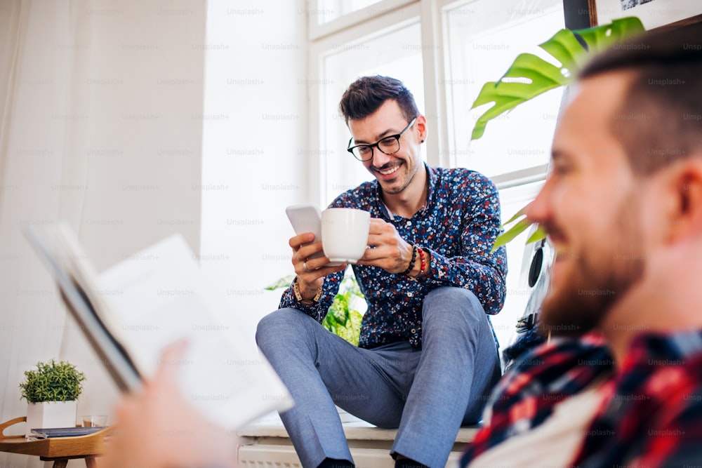 Un groupe de jeunes amis joyeux se détendant à l’intérieur, concept de partage de maison.