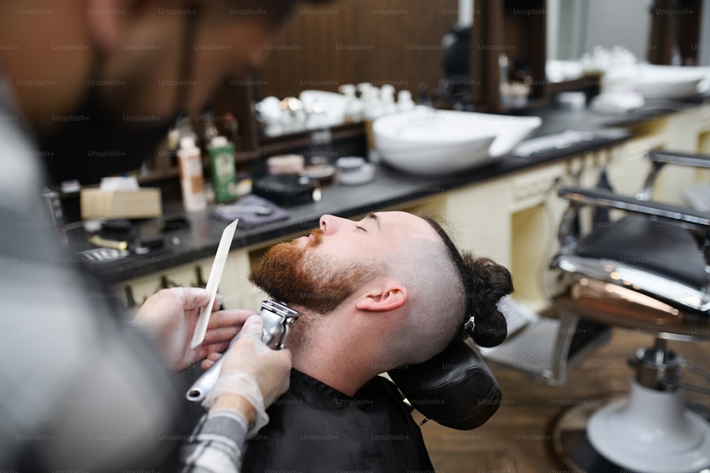 Un cliente joven que visita a un diseñador en una peluquería, sección media y primer plano.