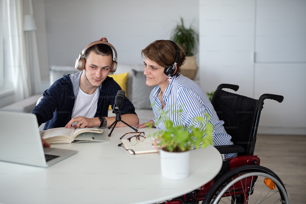 Personas discapacitadas felices sentadas en la mesa en el interior de casa, grabando podcast en casa.