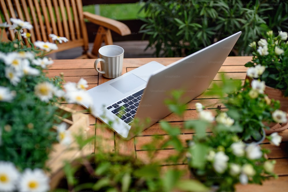 여름에 발코니에 있는 테이블에 있는 노트북과 커피의 상위 뷰, 야외 사무실 개념.