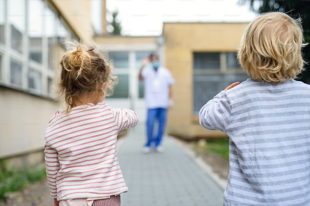 Foto Vista trasera de niños saludando al padre médico frente al hospital,  coronavirus y concepto de aislamiento. – Eslovaquia Imagen en Unsplash