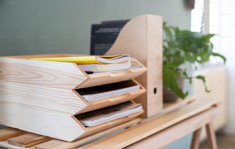 Paper and document wooden tray holders and organisers on desk with plant, natural decor concept.