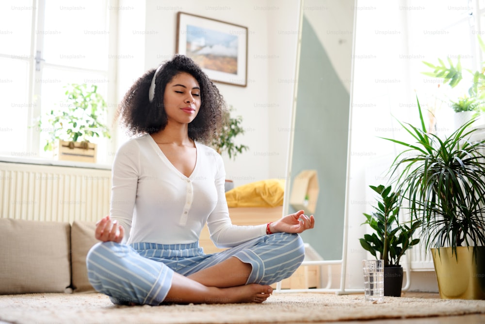 Ritratto di giovane donna rilassata all'interno a casa, facendo esercizio di yoga.