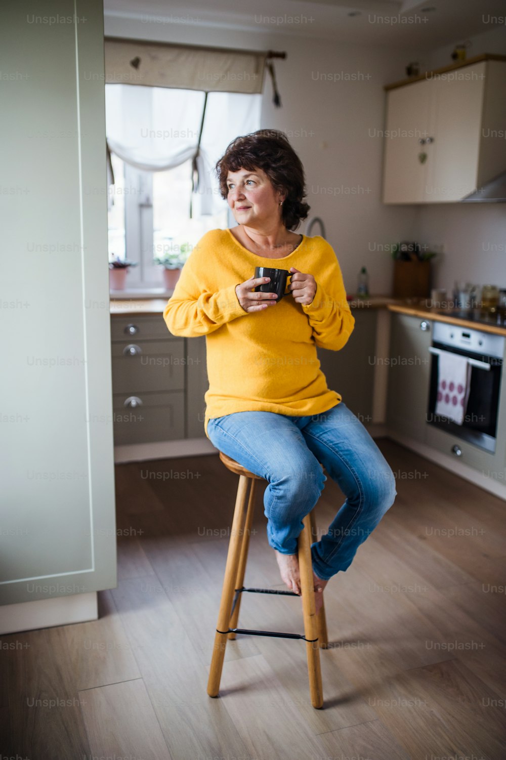 Portrait of senior woman with cup of coffee at home, relaxing.