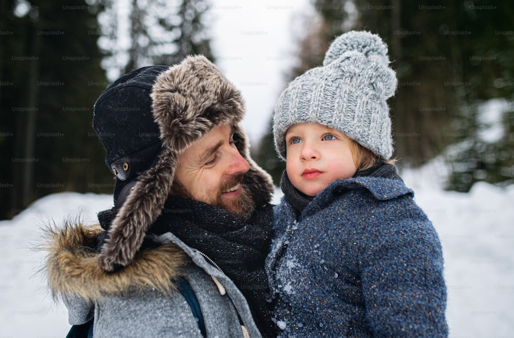 Close-up portrait of father with small son in snowy winter nature, talking.